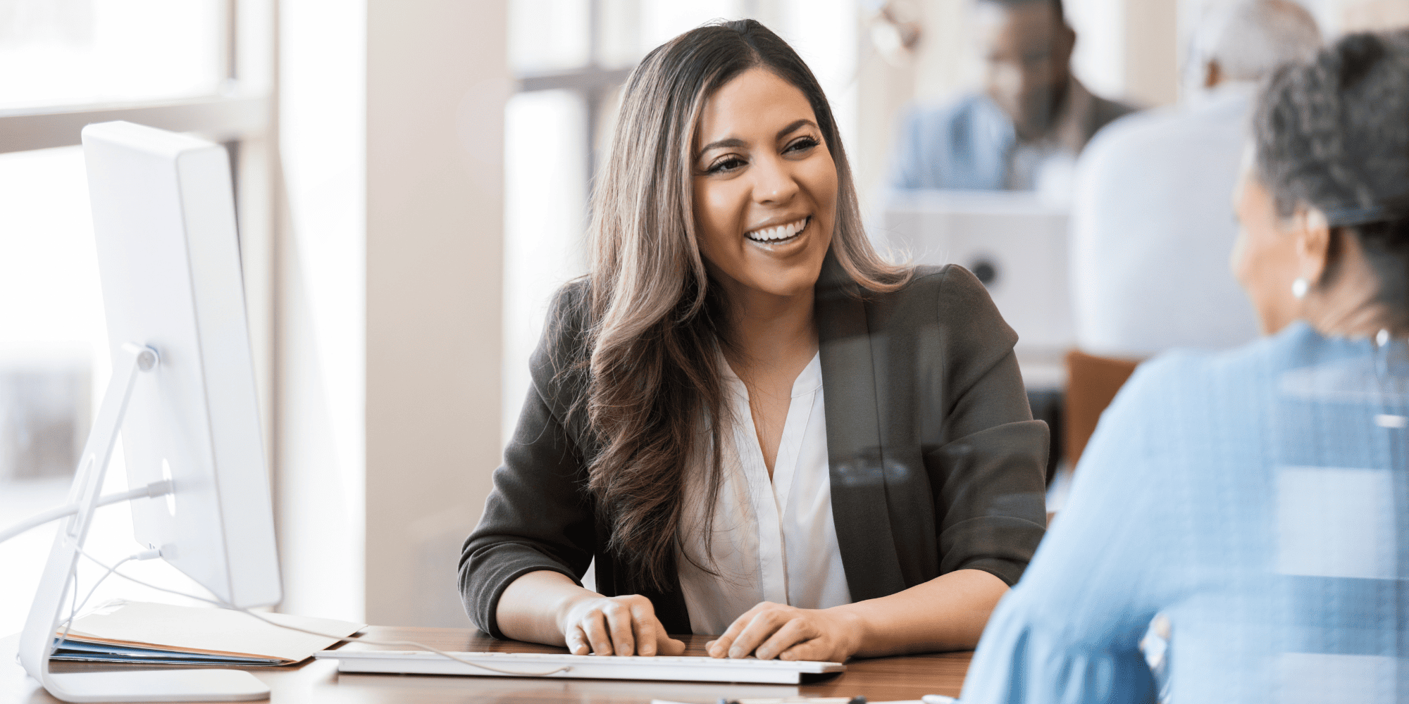 Stock Image of a Bank Employee at a Computer Helping a Woman Get a Credit Card for Home Remodel