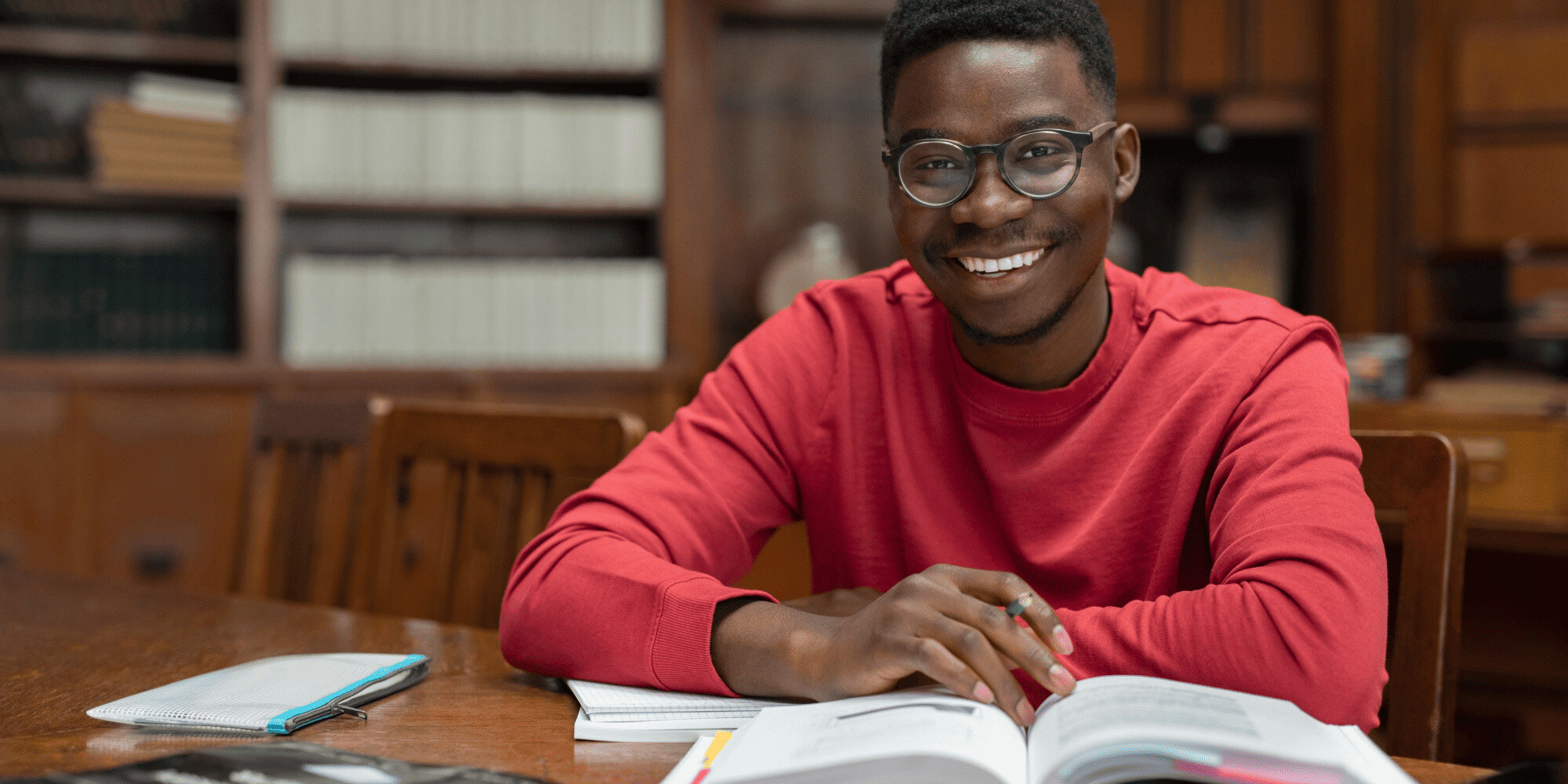 Stock Image of Young Man in a Red Shirt Studying in a Library 