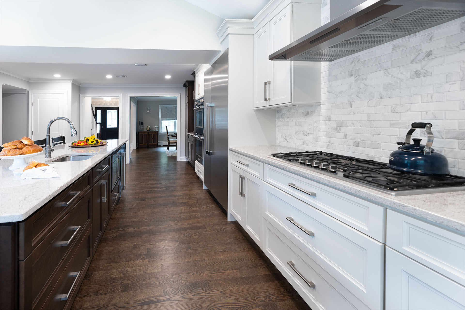 Large Kitchen Remodel with White Marbled Backsplash and Dark Island