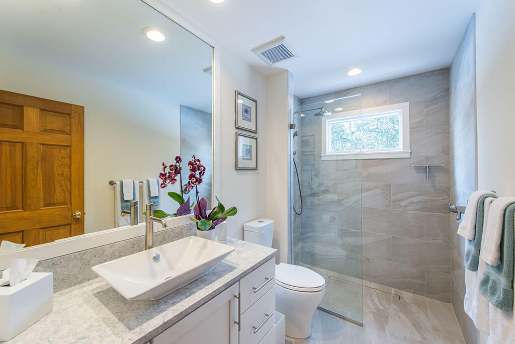 Hall bathroom remodel with curbless, roll-in shower with frameless glass panel, vessel sink, quartz counter and white shaker cabinet vantity in Chester, NJ renovated by JMC Home Improvement Specialists